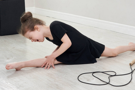 做劈叉小女孩在家里做劈叉操和体操,感到很痛苦照片