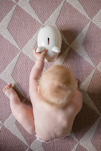 宝宝的钱一个婴儿伸手去拿小猪存钱罐的俯视图照片