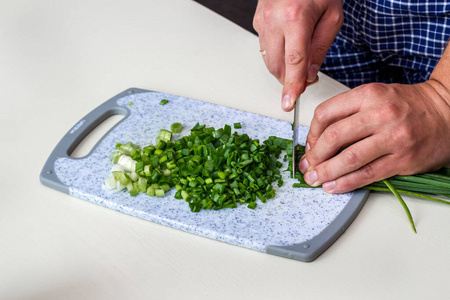 厨房菜板特写手拿刀切菜,切葱.鲜葱片.在厨房里煮蔬菜.