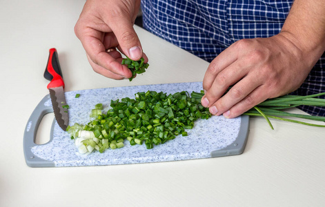 特写手拿刀切菜,切葱.鲜葱片.在厨房里煮蔬菜.