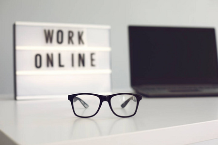 在线工作。一张桌子上有一个商人远程工作的笔记本电脑上的眼镜。