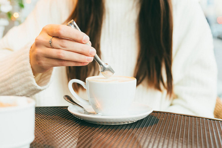 一个年轻女孩在咖啡里放糖