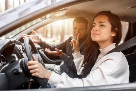 微笑的年轻女子在旅途中与男人一起开车自信的白种人女人开车,而男人