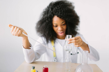 一位年轻漂亮的非洲裔美国女孩的画像，研究化学的学生在化学实验室里进行研究。科学家分析试管。