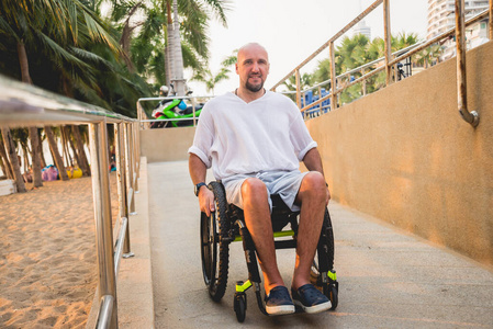 坐轮椅的残疾人在斜坡上走向海滩。