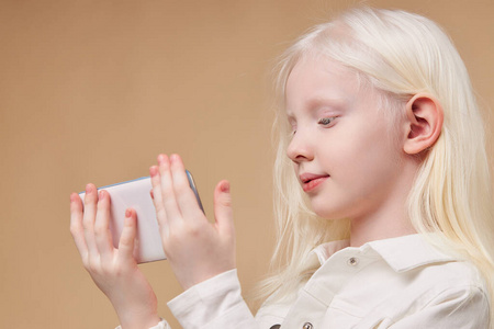 病儿白化病儿童手拿白色智能手机被隔离照片