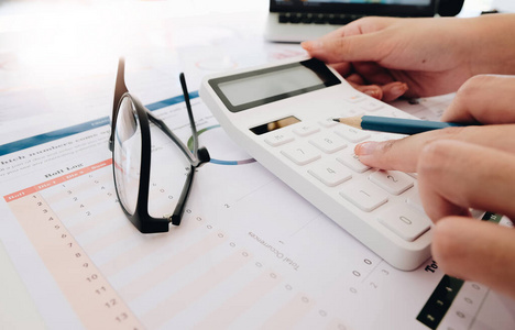 Close up Business woman using calculator and laptop for do math 