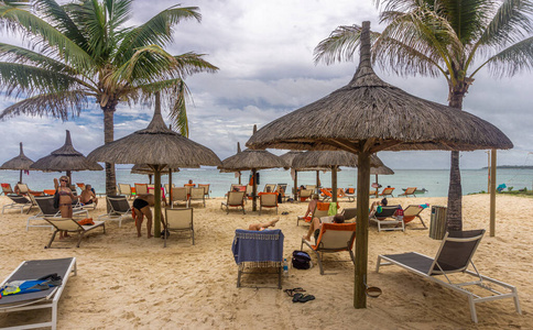 热带沙滩上的茅草屋和沙滩椅照片