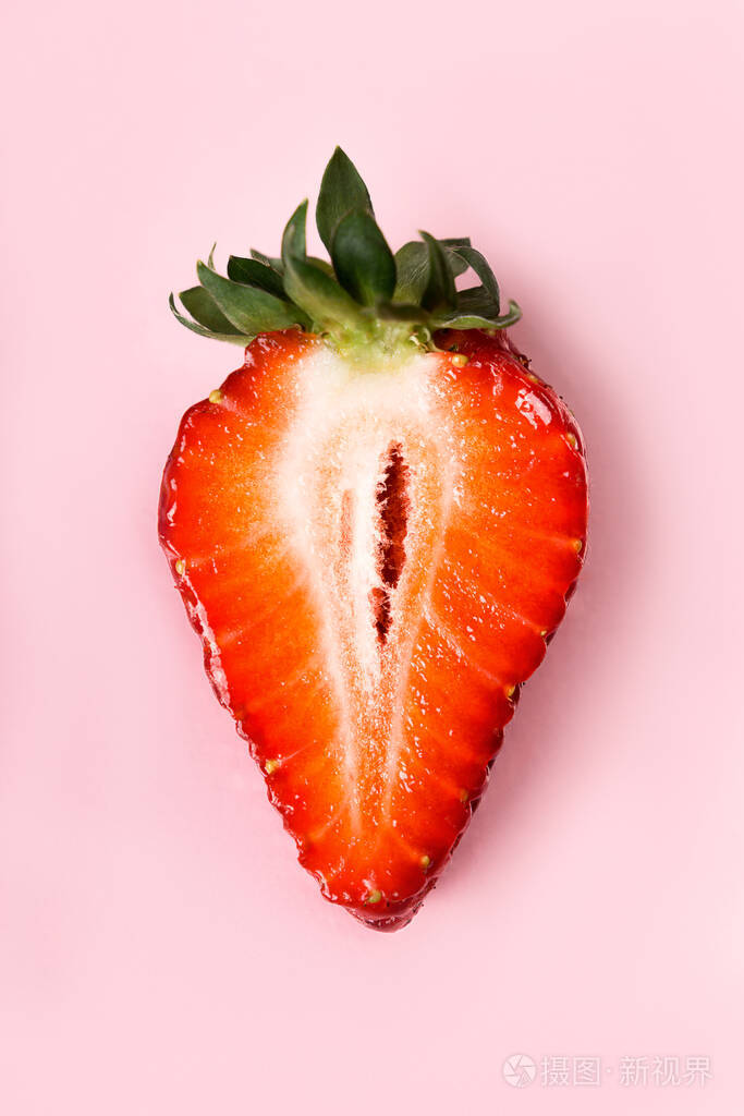 漂亮多汁的半草莓在粉红色的背景上草莓片宏