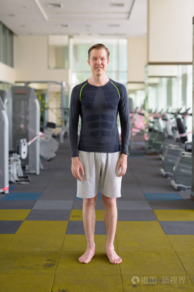 covid19期间快乐的年轻帅哥在健身房微笑的全身照片