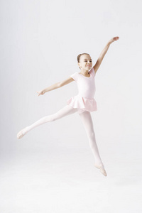 可爱的青春期前芭蕾舞演员在白色背景上跳跃