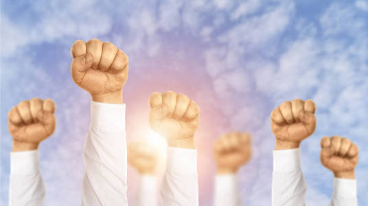 迎五一画决心取得成功.创意拼贴画,商务人士举起拳头迎着蓝天照片