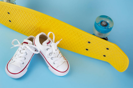 白色运动鞋的照片在滑板或便士板在蓝色背景。