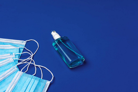 蓝色背景上有洗手液的医用口罩照片