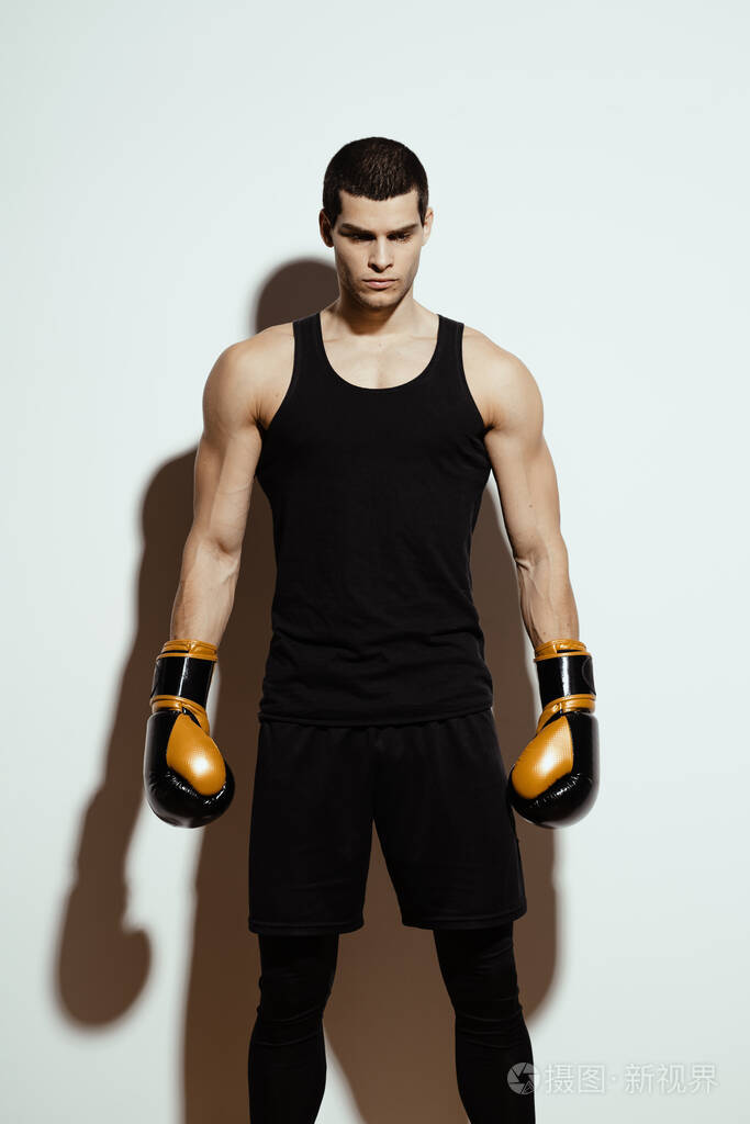 身材高大英俊的运动员戴着拳击手套在白色背景上摆姿势