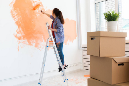 在公寓里修理。快乐的女人用油漆粉刷墙壁。