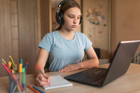 疫情网课严肃的少女1214岁,家用耳机,笔记本电脑课程,笔记本电脑彩色