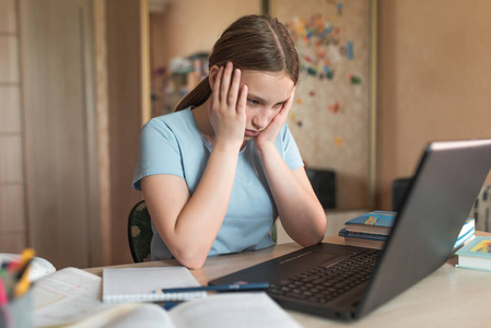 1214岁的女孩累得心烦意乱,在家里,上笔记本电脑课,看视频阅读作业.