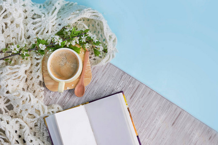 舒适的家静物生活:一杯热咖啡,春天的鲜花,打开的书与温暖的格子.