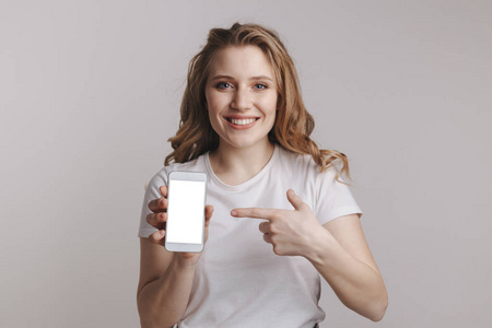 iphone手手持一个年轻的女人拿着白色的iphone在白色的背景上照片