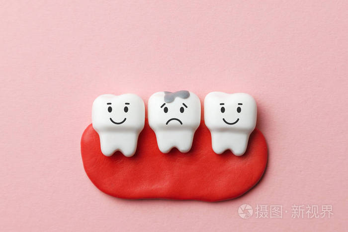 健康的白色牙齿在微笑，有龋齿的牙齿在粉红色的背景下悲伤。