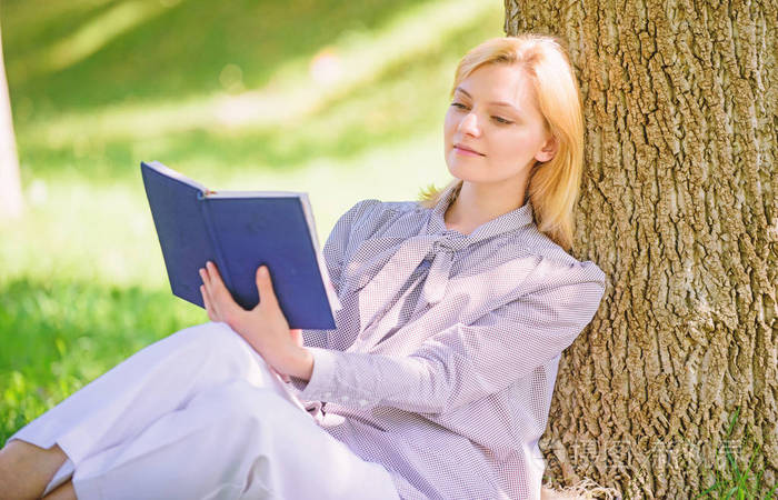 女性自我提升女孩靠在树上在公园里放松坐在草地上自强书自我完善与