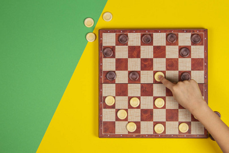 儿童手玩棋盘游戏在黄绿色背景上,俯视图照片