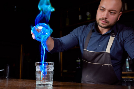 酒保调制热的酒精鸡尾酒,点燃酒吧.酒保准备了一杯烈酒.向酒吧开火.