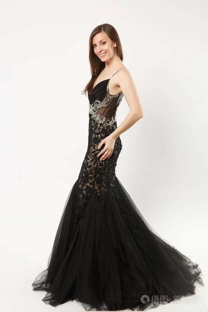 全身照片时尚模特女子穿着优雅的晚礼服黑色长袍在白色墙壁上单独摆出