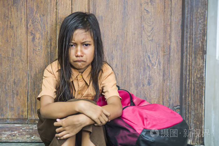 78岁的孩子穿着校服坐在室外的地板上哭着伤心沮丧