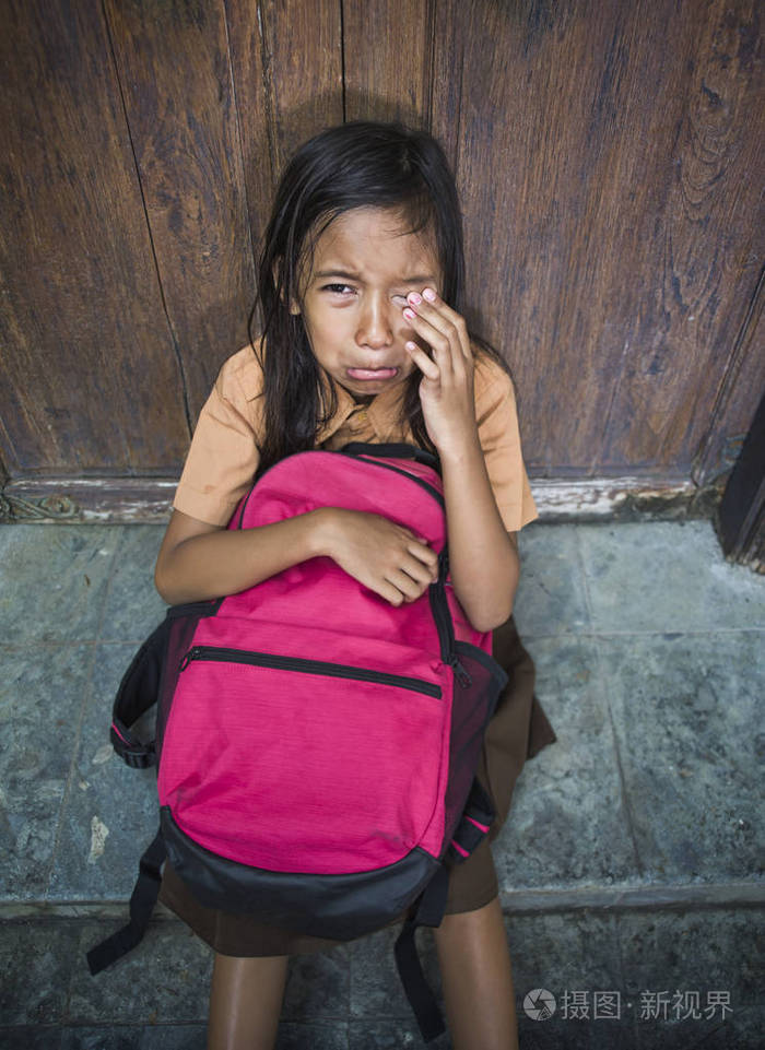 78岁的孩子穿着校服坐在户外的地板上哭着伤心沮丧