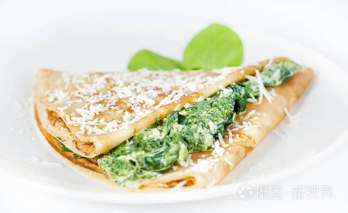 Thin delicious pancake with spinach on white 