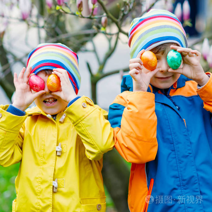 两个小男孩和朋友在春天花园,户外进行传统的复活节彩蛋狩猎.