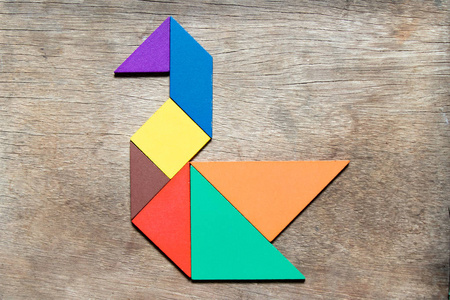 传统符合木制背景上天鹅形状的彩色七巧板照片