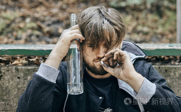一个男人拿着一杯伏特加的特写镜头喝醉的年轻人酗酒痛苦怜悯绝望依赖