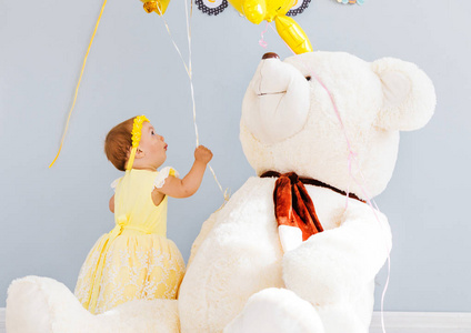带着气球和一只大玩具白熊的小女孩照片