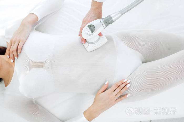 特写美容专家在女性腹部做液化石油气按摩