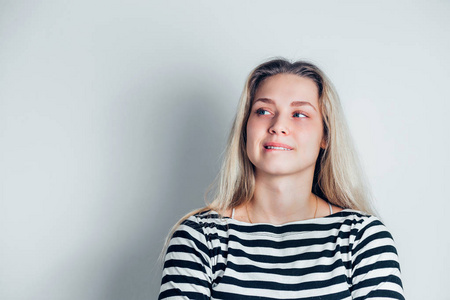 厌恶不满的表达室内特写,年轻不满的女人咬下嘴唇在白色背景上的复制