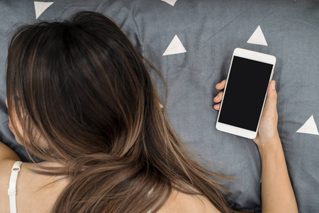 躺在床上用智能手机睡觉的女人图片