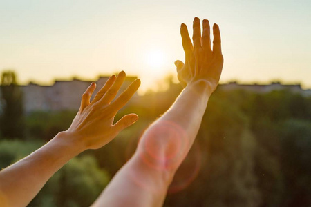 双手张开向夕阳,冥想,宗教,祈祷,房子里敞开的窗户的背景,城市的轮廓