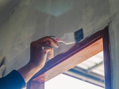 刷墙背景工人手用滚筒和刷子刷墙的特写镜头照片
