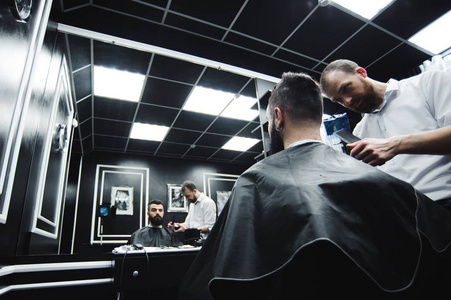 理发师在理发店给男人理发,理发师给年轻人做发型.照片