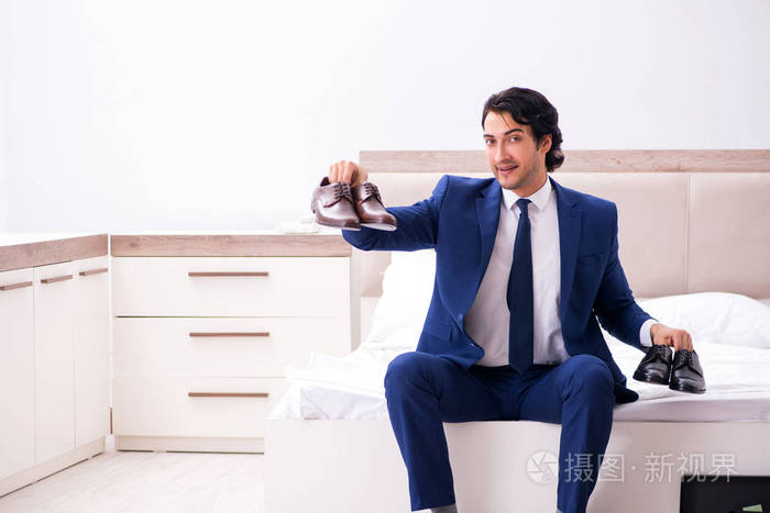 Young handsome businessman choosing shoes at home 