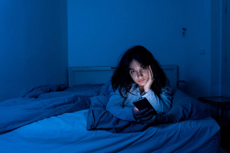睡网床迷人的拉丁女人沉迷于手机和互联网,深夜躺在床上睡不着觉照片