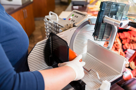 切腊肉肉店的女人用机器切腊肉照片