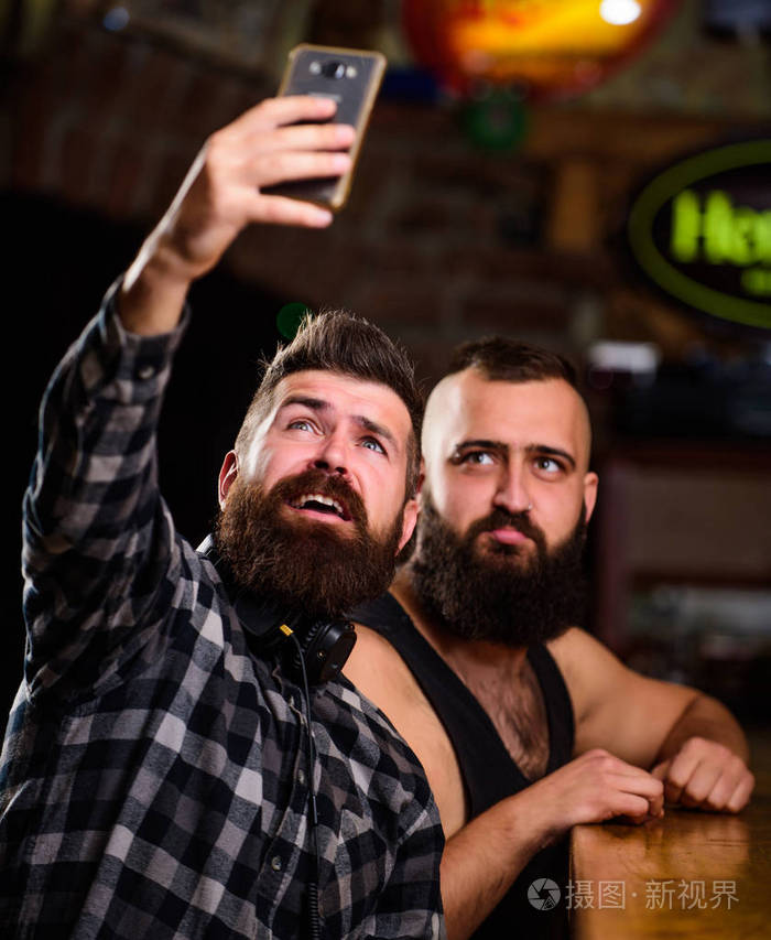 男人拿着智能手机自拍概念将自拍发送到好友社交网络酒吧里喝啤酒的人