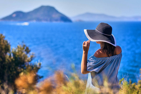 一位戴着沙滩帽的美女,在阳光明媚的日子里欣赏着蓝天海景