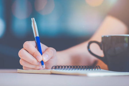 女商人的手正在用钢笔在笔记本上写字.照片