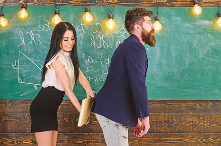 有胡子的男人被性感的学生惩罚,背景是黑板照片