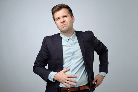 欧洲穿西装的年轻人胃痛绞痛或肠胃胀气照片